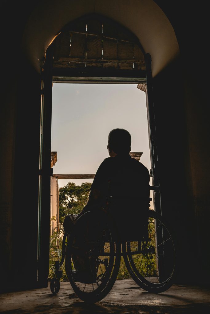 pexels photo 3057504 3057504 Silhouette of a man in a wheelchair gazing outdoors, symbolizing solitude and reflection.