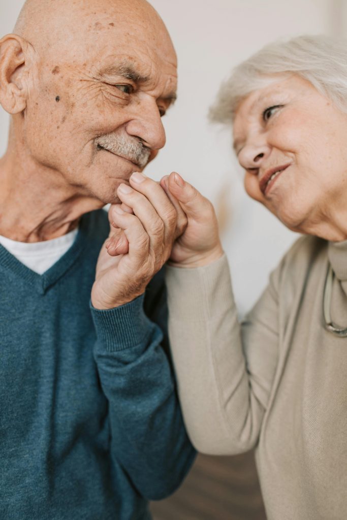 pexels photo 5790837 5790837 An elderly couple expressing love and affection, holding hands indoors.